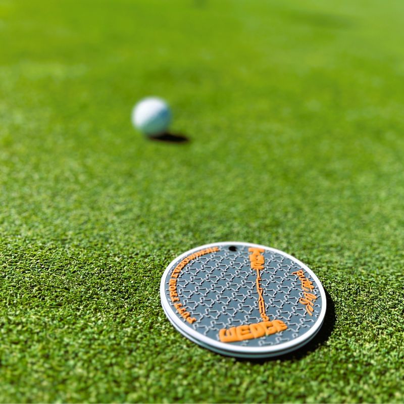 Golf ball and putt life golf putting disc marker on a green golf putting surface