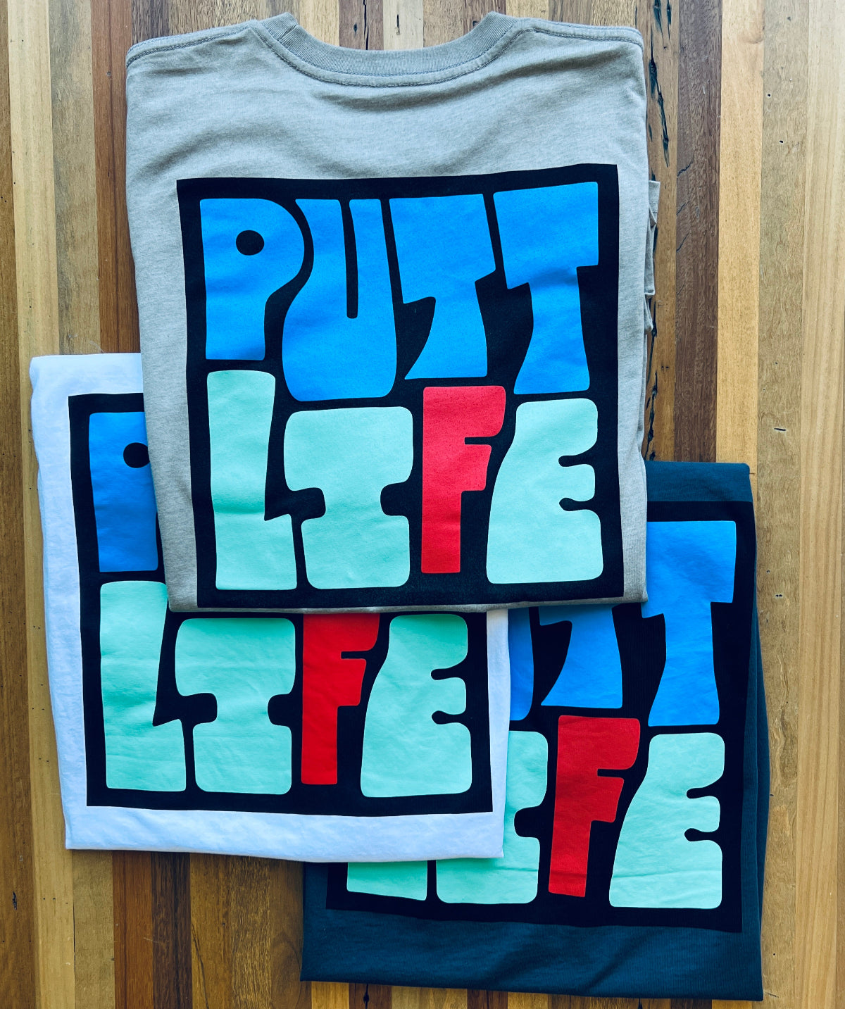 Putt Life Golf navy blue white gray t-shirts with colorful 'PUTT LIFE' text on the back view