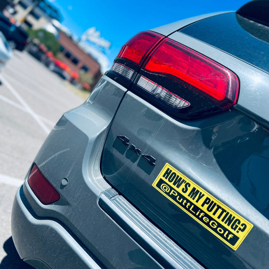 Putt Life Golf yellow bumper sticker with the text 'HOW'S MY PUTTING?' and an @ symbol, placed on the rear of a gray car